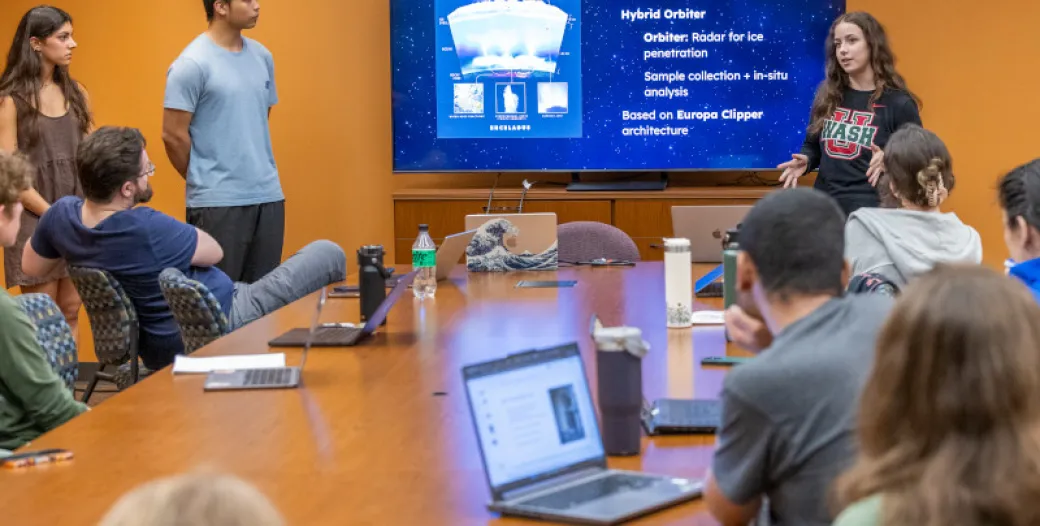 "students in a conference room listen to a powerpoint presentation"