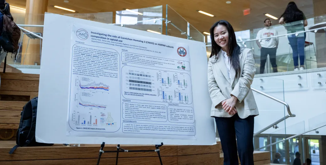 Young woman standing and smiling next to undergraduate research poster