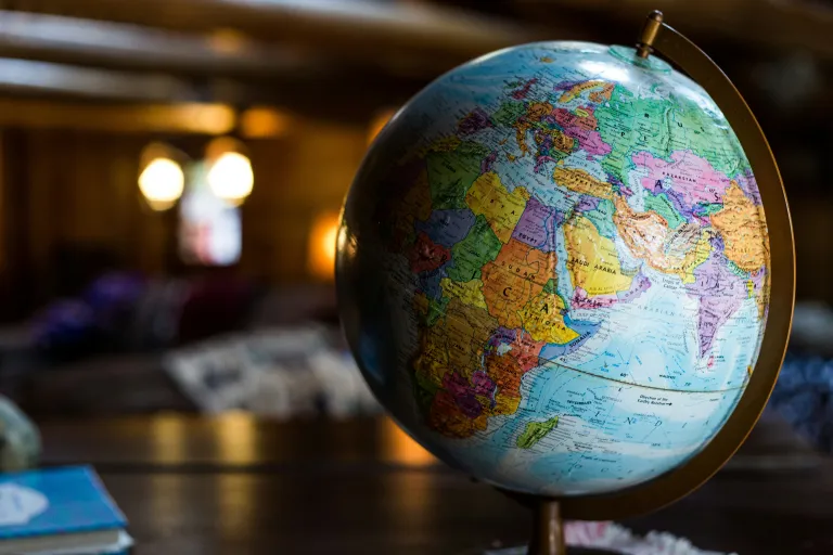 A colorful globe sits on a table with lights shining behind